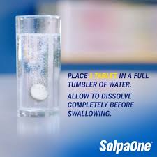 A SolpaOne 1000mg effervescent tablet from Solpadeine dissolves and fizzes in a tall glass of water. Instructions: Place 1 tablet in a full tumbler, allow to dissolve completely for fast absorption. SolpaOne logo at the bottom right.