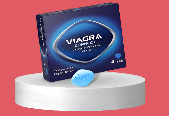 A box of Viagra Connect tablets is displayed on a white platform against a red background. The box is blue with white text, showing 50 mg film-coated tablets containing sildenafil. A single blue pill with Pfizer engraved is placed in front.