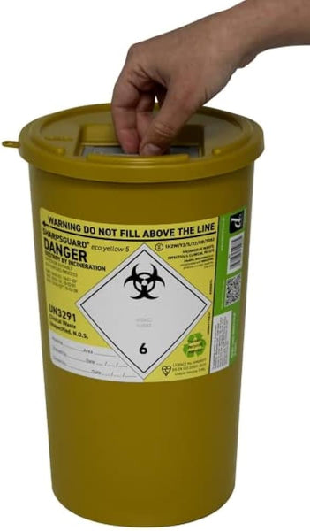 A hand gently closes the lid of a Sharpsguard Yellow 5L, a container with warnings and a biohazard symbol, designed by Sharps for safe disposal of needles, ensuring hygiene.