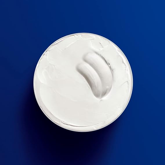 A white bowl of smooth, creamy yogurt rests against a solid blue background. Its swirled surface resembles the texture of Nivea Creme by Nivea (200ml), promising an intense moisture experience.