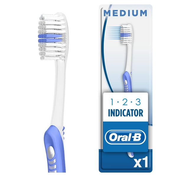 Image of an Oral-B Manual 1-2-3 Indicator Toothbrush featuring white and blue bristles with indicator bristles for replacement timing. The handle has a white and blue grip, and the packaging displays 1 2 3 Indicator with the Oral B logo.