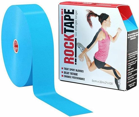 A roll of Rocktape Kinesiology 5cm Tape - Electronic Blue rests next to its box, which shows an athlete applying the tape to a shoulder and leg. The RockTape brand is known for elastic support in injuries and performance enhancement in sports.