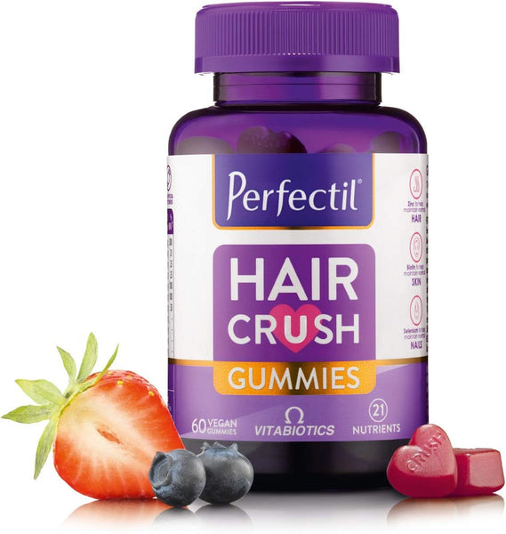A bottle of Vitabiotics Hair Crush Gummies (60) by Vitabiotics, with 60 vegan gummies, is shown with berries and heart-shaped gummies. The label highlights Biotin for hair growth and benefits for healthy hair, skin, and nails.