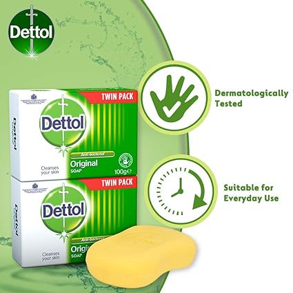 Image of Dettol Original Soap Twin Pack (2 x 100g) and a yellow moisturizing bar. Packaging highlights Original and Cleanses your skin. Icons show its dermatologically tested, antibacterial, and ideal for daily use. Green background with splash effect.