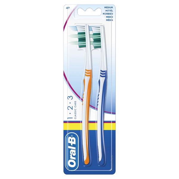 The Oral-B 1-2-3 Classic Care Medium Toothbrush Twin Pack includes two manual brushes with ergonomically designed handles. They have distinct orange and blue grips, and the packaging clearly displays the Oral B brand and product details.