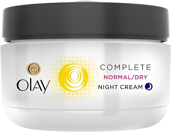 A white jar of Olay Complete Care Night Cream (50ml) features a sleek black lid, the iconic Olay logo, and a vibrant yellow swirl on the label, emphasizing its dual function as a nourishing night moisturizer for normal to dry skin.