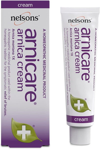 A box and tube of Nelsons Arnicare Arnica Cream (30g) are shown. The purple and white packaging highlights its efficacy as a homeopathic solution for bruises, featuring an arnica plant image suitable for sensitive skin.