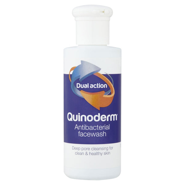 A 150ml bottle of Quinoderm Antibacterial Face Wash features a white cap and a label with Dual Action and Deep pore cleansing for clean & healthy skin, ideal for spot-prone skin, set against a blue/purple background with orange and blue arrows.