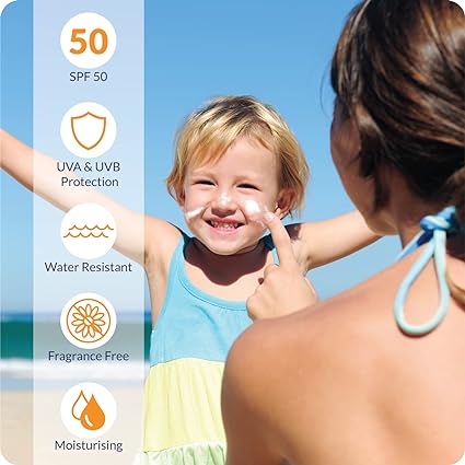 At the beach, a woman applies UltraDexs Uvistat Sun Cream SPF50 (125ml) to a smiling child’s face, showcasing its UVA & UVB protection, water resistance, and moisturizing properties against the clear blue skies and ocean backdrop—an essential summer ritual.