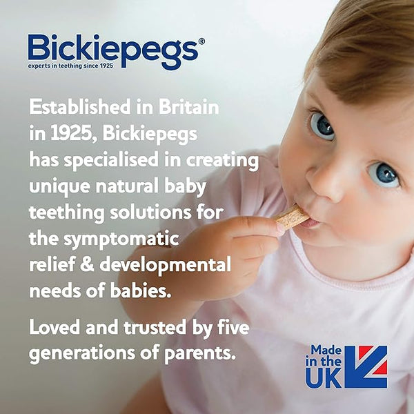 A baby in a pink outfit joyfully bites a Bickiepegs Natural Teething Biscuit, made by Bickiepegs, a British company trusted for generations since 1925 for natural teething solutions with ingredients proudly from the UK.