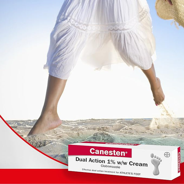 A person in a flowing white dress strolls barefoot on a sandy beach, with a box of Canesten Dual Action Cream (30g) in the foreground, highlighting its clotrimazole formula as a trusted antifungal treatment for athletes foot.