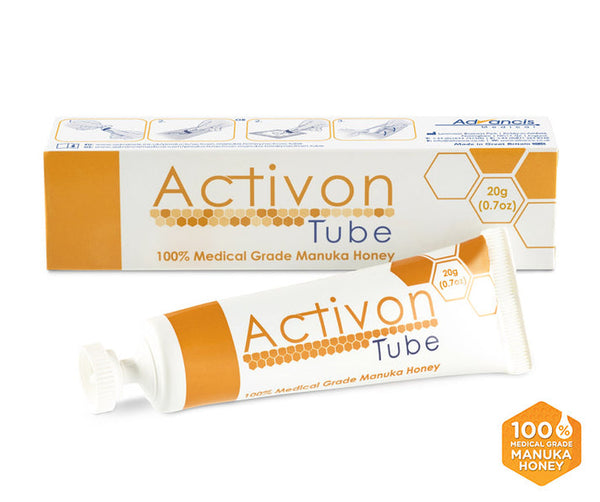 An Activon Manuka Honey Tube (25g) by Advancis, ideal for skincare and natural healing, sits next to its honeycomb-designed box. The packaging confidently highlights its 100% medical grade quality with a small orange label.