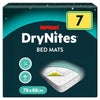 The Huggies DryNites Bed Mats (7) by Huggies come in a 78x88 cm size and feature prominent packaging with a large yellow number 7, a clear product image of an absorbent bed mat on a mattress, and icons highlighting up to 12 hours of protection and the stick & stay feature. These waterproof bed mats provide dependable overnight comfort and protection.