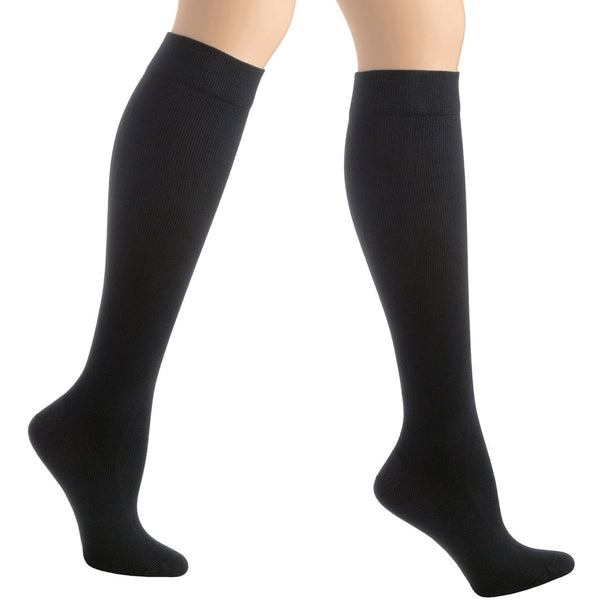 A pair of legs elegantly stands on tiptoe wearing Activa Unisex Socks Class 2 Small, showcasing the smooth, stretchy fabric. Ideal for enhancing circulation and preventing deep vein thrombosis. The backdrop is plain white.