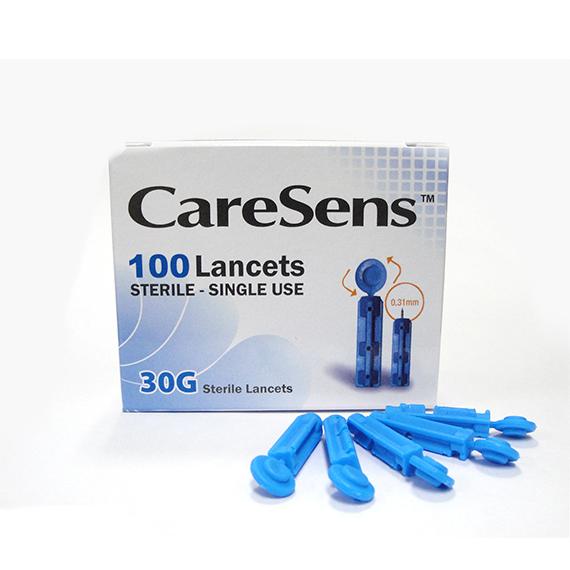 A box of Spirit Healthcares Caresens Lancets 0.31mm/30g (100-pack) displays eight blue lancets strewn before it. With a gradient blue design, these sterile, single-use lancets are perfect for capillary blood sampling.