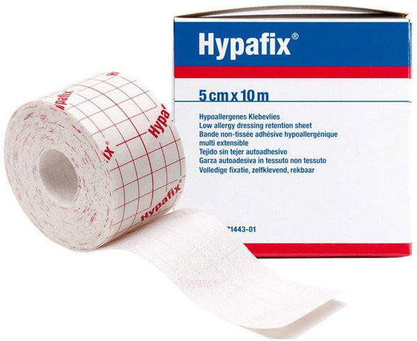A roll of Hypafix Hypoallergenic Dressing Tape (5cm x 10m), partially unrolled, rests beside its branded box displaying product and dressing fixation details in various languages.
