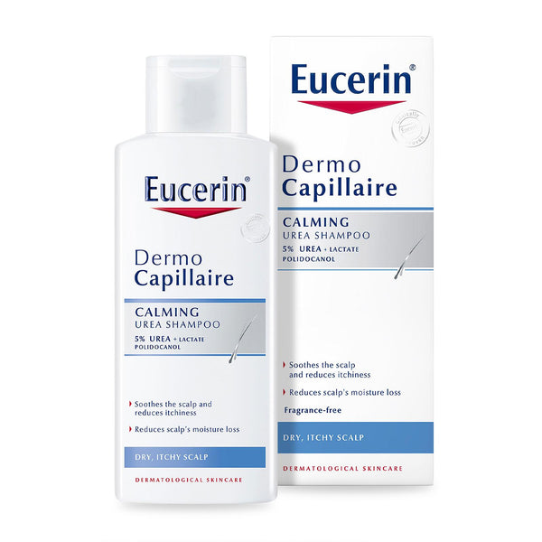 A white bottle of Eucerin Dermo-Capillaire Calming Urea Shampoo 250ml for dry, itchy scalps is displayed beside its packaging. The label highlights its soothing effects, fragrance-free formula, and contains 5% Urea and Lactate for effective relief.