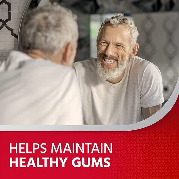 An elderly man with a beard smiles in a mirror while wearing a white t-shirt. A red banner below reads, Helps Maintain Healthy Gums, emphasizing the importance of oral health with products like Corsodyl Daily Mouthwash Cool Mint (500ml) for effective plaque removal.