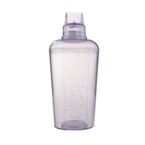 The Able Spacer 2 is a transparent plastic inhalation chamber bottle, featuring a wide base and narrow top with a spout. It includes instructional illustrations on the side, likely indicating steps or measurements for a metered dose inhaler.