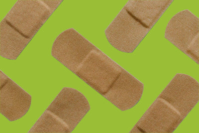 Adhesive bandages arranged diagonally on a bright green background. The bandages are light brown and have a rectangular shape with rounded edges.