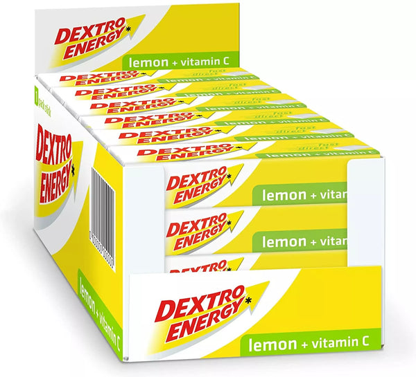 A 24-pack box of Dextro Energy Tablets-Lemon, ideal for energy boosts, features yellow and white packaging labeled lemon + vitamin C with a red and yellow starburst Dextro Energy logo.