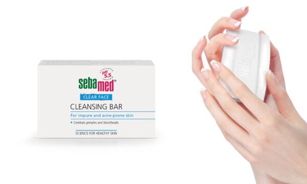 A box of Sebamed Cleansing Bar 100g for Eczema-Prone Skin Treatment is on the left, with pore-deep cleansing details. On the right, hands hold the white bar aimed at impure, acne-prone skin while maintaining a pH of 5.5 for effective treatment.