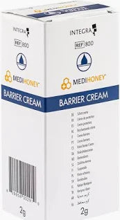 A white Medihoney Barrier Cream box, with blue and yellow detailing, highlights its Antibacterial Honey formula. The front features the product name and a diagram; one side shows a barcode. Includes 20 sachets of 2g cream each.