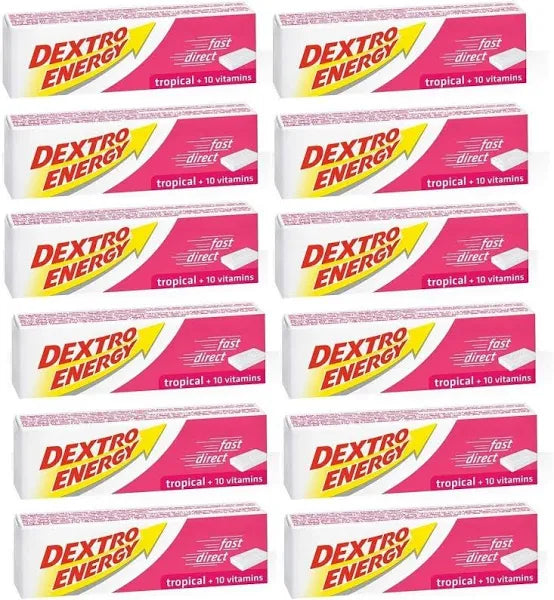 Twenty-four packs of Dextro Energy Tablets-Tropical, each branded in pink and yellow for an energy boost and immune support with 10 vitamins, are neatly arranged in three columns and four rows.